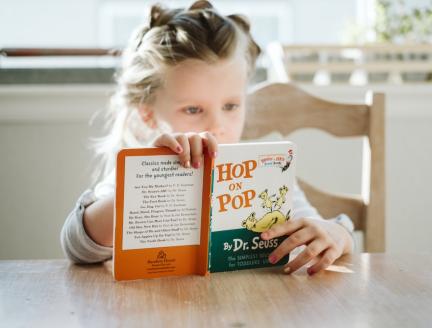 Child concentrating reading book alone, Photo by Josh Applegate on Unsplash