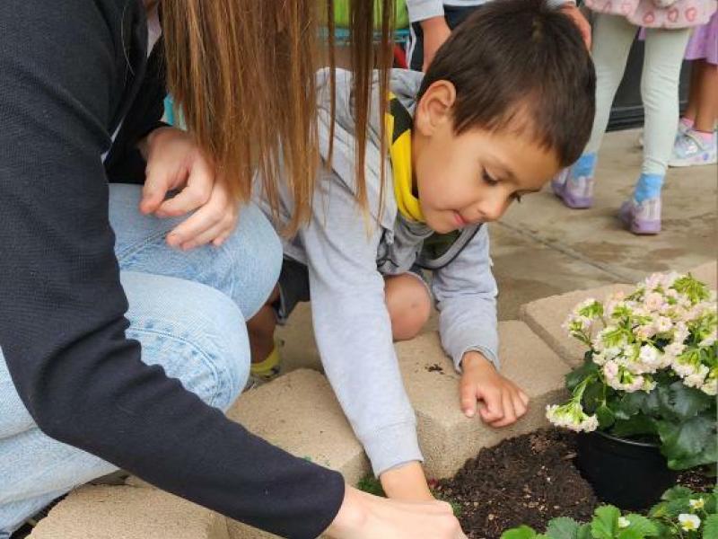 Child Exploring the World Through Language with teacher in the garden